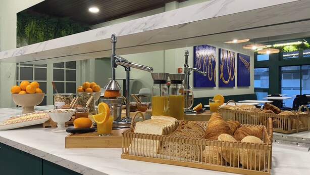 Un bufé de desayuno con naranjas, pan y dispensadores de jugo.