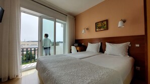 Habitación de hotel con dos camas, un balcón y vistas a la ciudad.