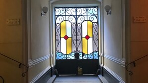 Un couloir menant à une porte ornée d’un panneau de verre décoratif.
