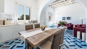 Een moderne keuken met witte kastjes, een houten eettafel en een vloer met een blauw en zwart patroon.