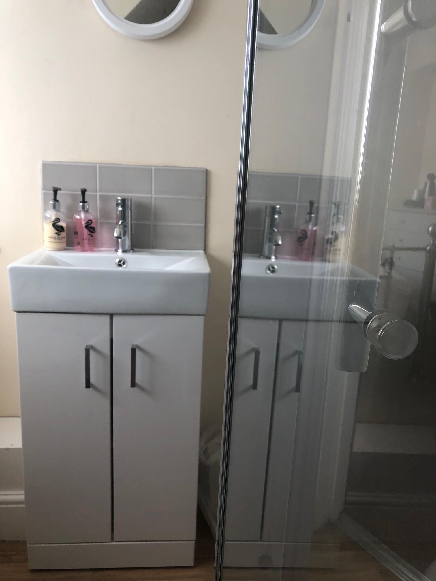 Un baño con tocador blanco, un espejo y dos botellas de champú.