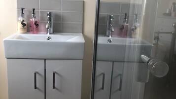 Un baño con tocador blanco, un espejo y dos botellas de champú.