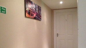 Un couloir avec un panneau indiquant la sortie de secours, une porte et un tableau accroché au mur.
