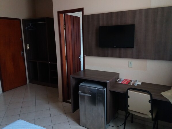 A compact room with a kitchenette, a small refrigerator, a wooden desk, and a chair. - Hotel Central (Porto Velho)