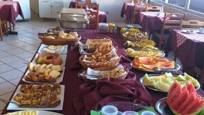 A buffet setup with various food items and a dining area with tables and chairs. - Hotel Central (Porto Velho)