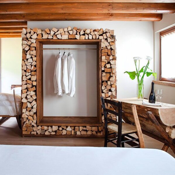 A hotel room with a stone-framed picture, a dining table with chairs, and a bed. - Wine Relais Cà Piadera (Tarzo)