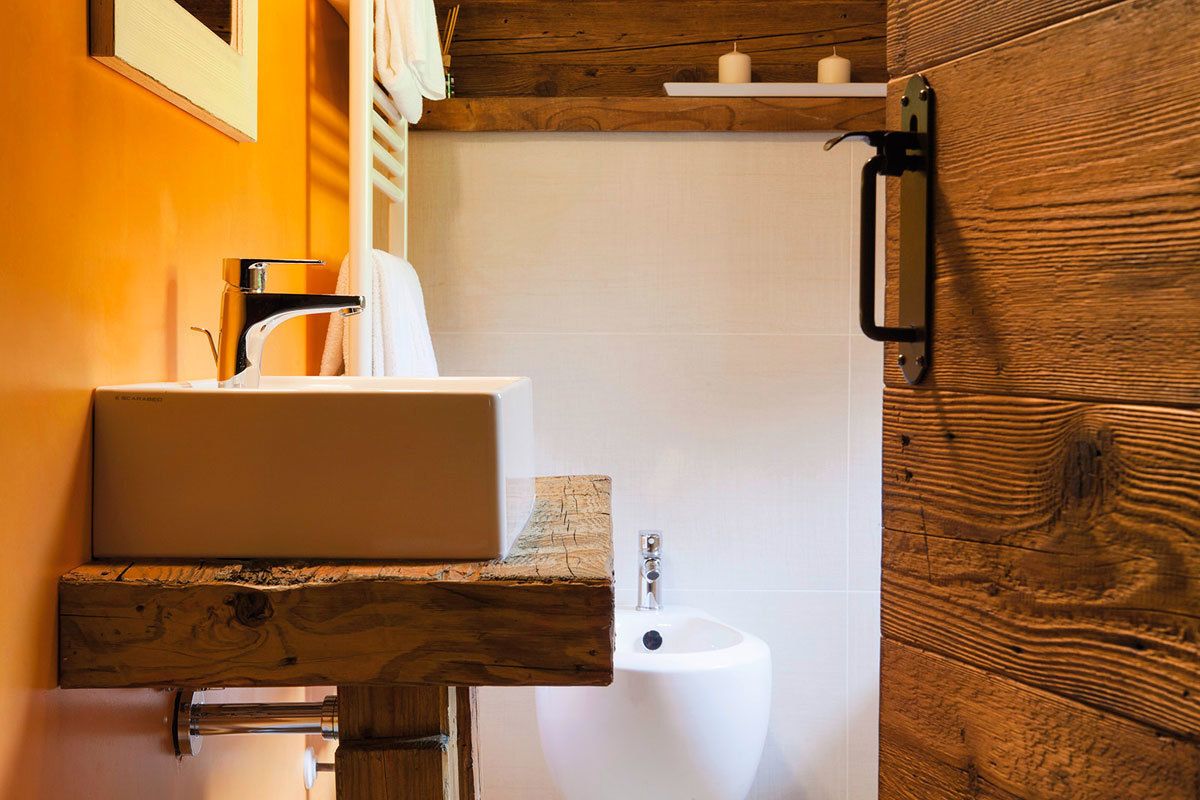 A bathroom with a wooden vanity, a white sink, and a bidet.