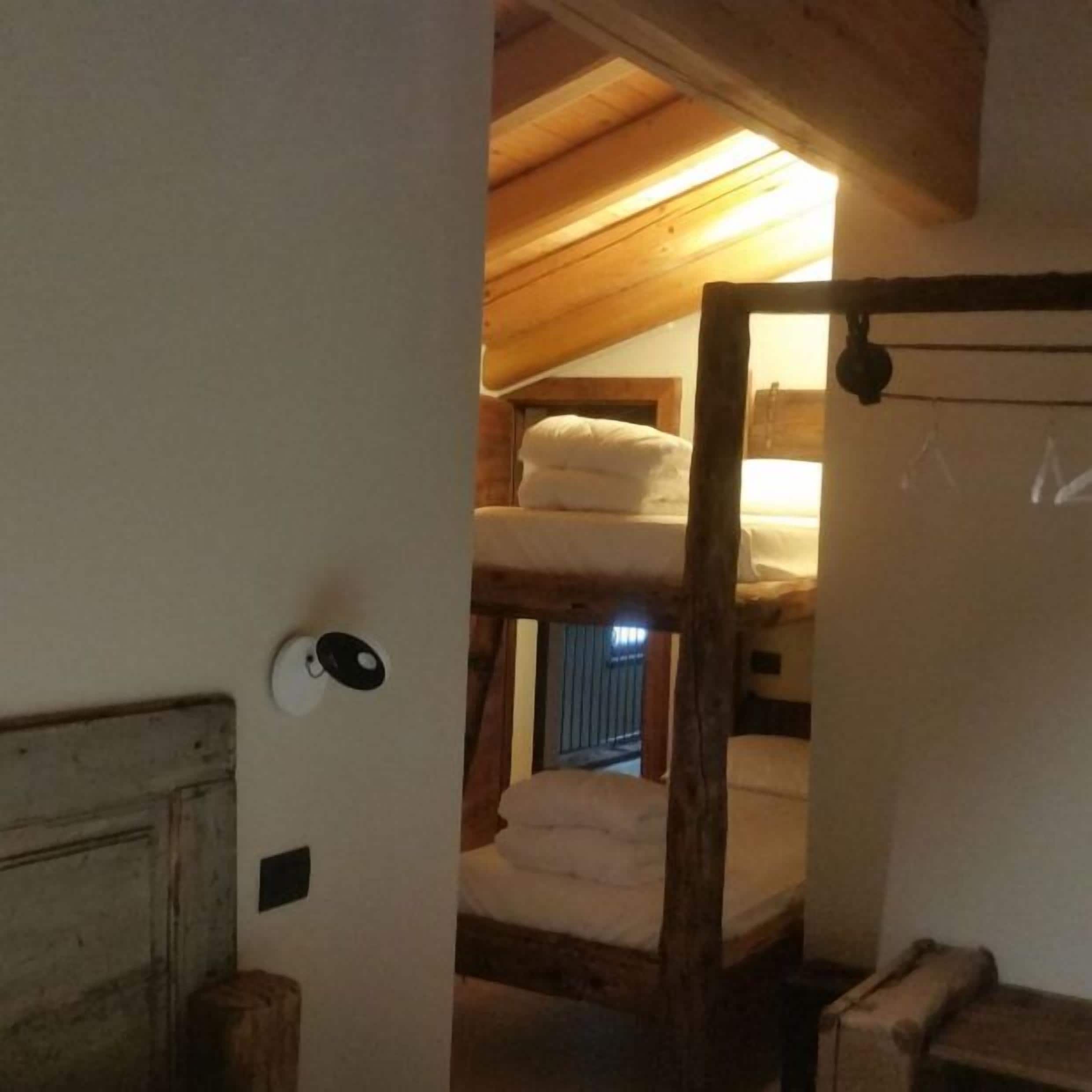 A rustic room with a wooden ceiling, a bunk bed, and a door with a round handle.