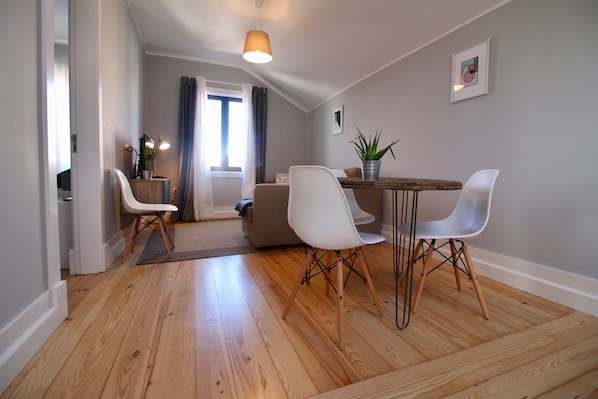 Un espace repas moderne avec une table en bois, des chaises blanches et une plante en pot.