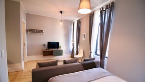 Een moderne slaapkamer met een groot bed, een televisie, een bureau en een stoel.