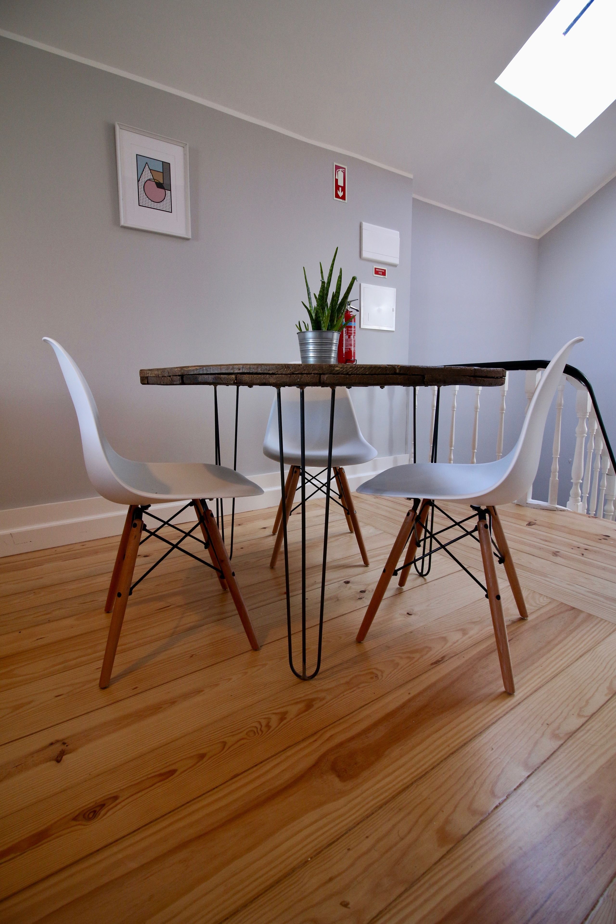 Een eetgedeelte met een houten tafel, twee witte stoelen en een potplant.