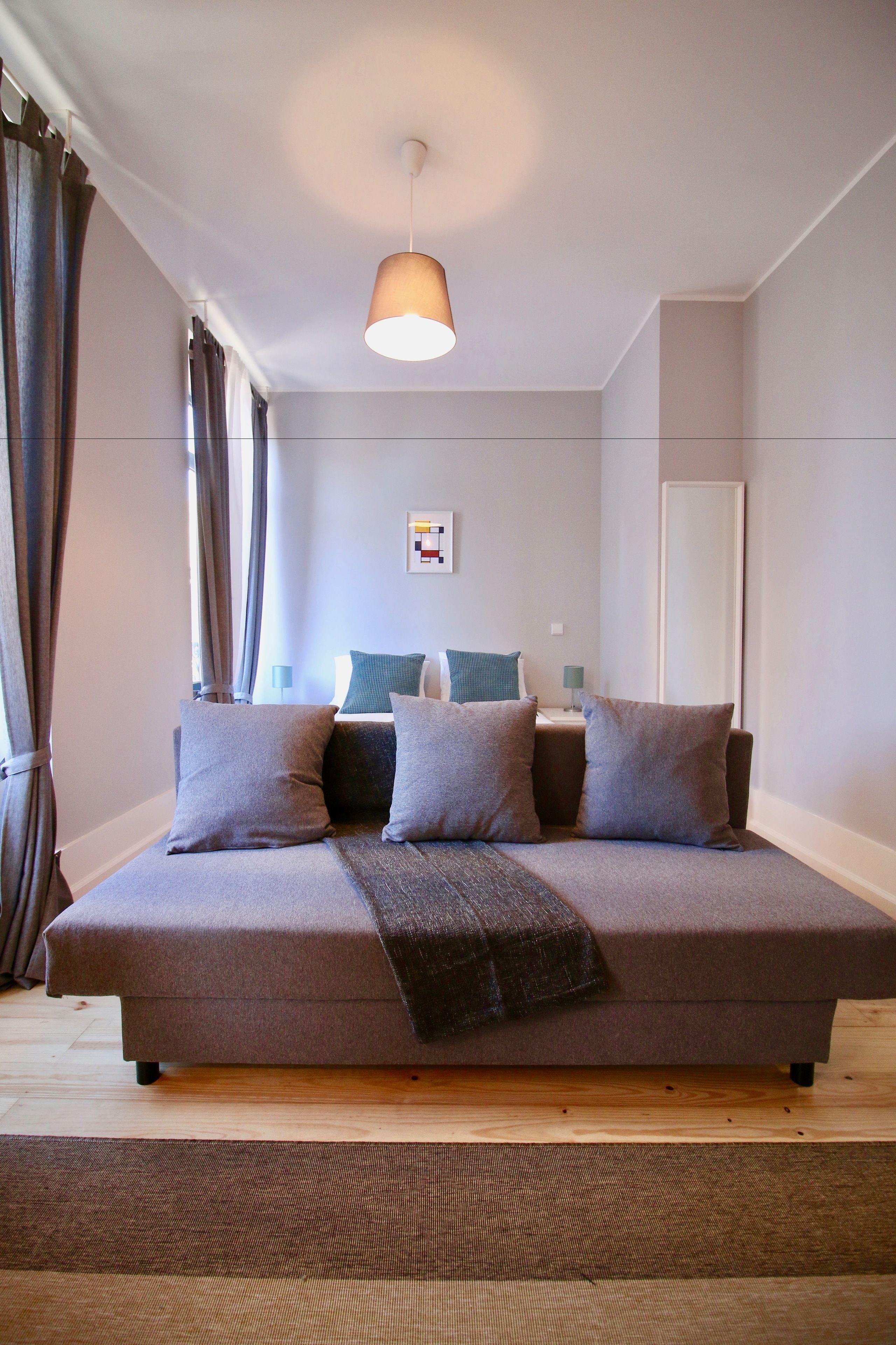 A modern bedroom with a large bed, a bedside table, a lamp, and a mirror.