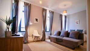 Een moderne woonkamer met een bank, salontafel, lamp en een plant.
