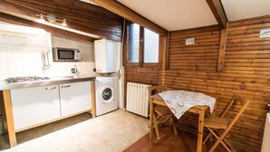 A compact kitchen with a microwave, sink, and washing machine. There is a wooden dining table with chairs. - Mono Verde (Turin)