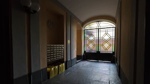 A hallway with a stained glass window, a clock, and a bench. - Mono Verde (Turin)