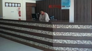 Una reception con pavimento in piastrelle decorate, una sveglia e un estintore appesi al muro.