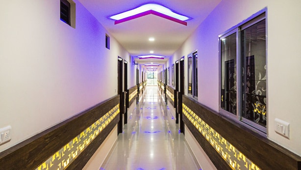 Un largo pasillo bien iluminado con piso reflectante, flanqueado por paneles de madera oscura y puertas de vidrio a ambos lados.