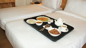 Habitación de hotel con dos camas, una bandeja con artículos de desayuno como cereales, café y un hervidor de agua.