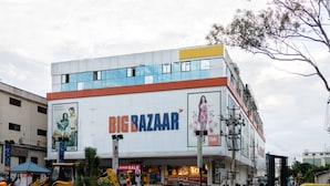 Un edificio de varios pisos con un llamativo letrero que dice 'BIG BAZAAR', con ventanas grandes y un techo plano.