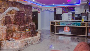 Un vestíbulo con pared de piedra, una recepción y un piso de mármol.