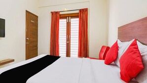 A hotel room with a bed, a wooden wardrobe, and a window with curtains. - OYO 9253 Champion Comfort (Bengaluru)