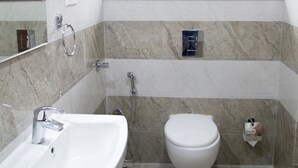 A bathroom with a white sink, a toilet, and a shower. - OYO 9253 Champion Comfort (Bengaluru)