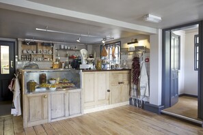 A kitchen with wooden cabinets, a glass display case, and various kitchen utensils. - Bourne Valley Inn (Andover)