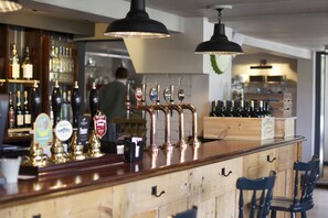 A bar area with multiple beer taps, wooden counter, and bar stools. - Bourne Valley Inn (Andover)
