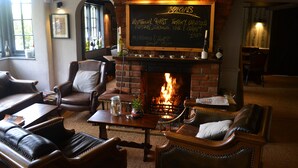 A cozy lounge area with leather seating, a fireplace, and a chalkboard menu listing specials.