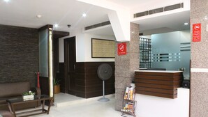 A reception area with a reception desk, a seating area with a sofa, a standing fan, and a 'No Smoking' sign.