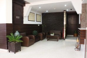 A modern lobby with a reception desk, seating area, and a dark textured wall.