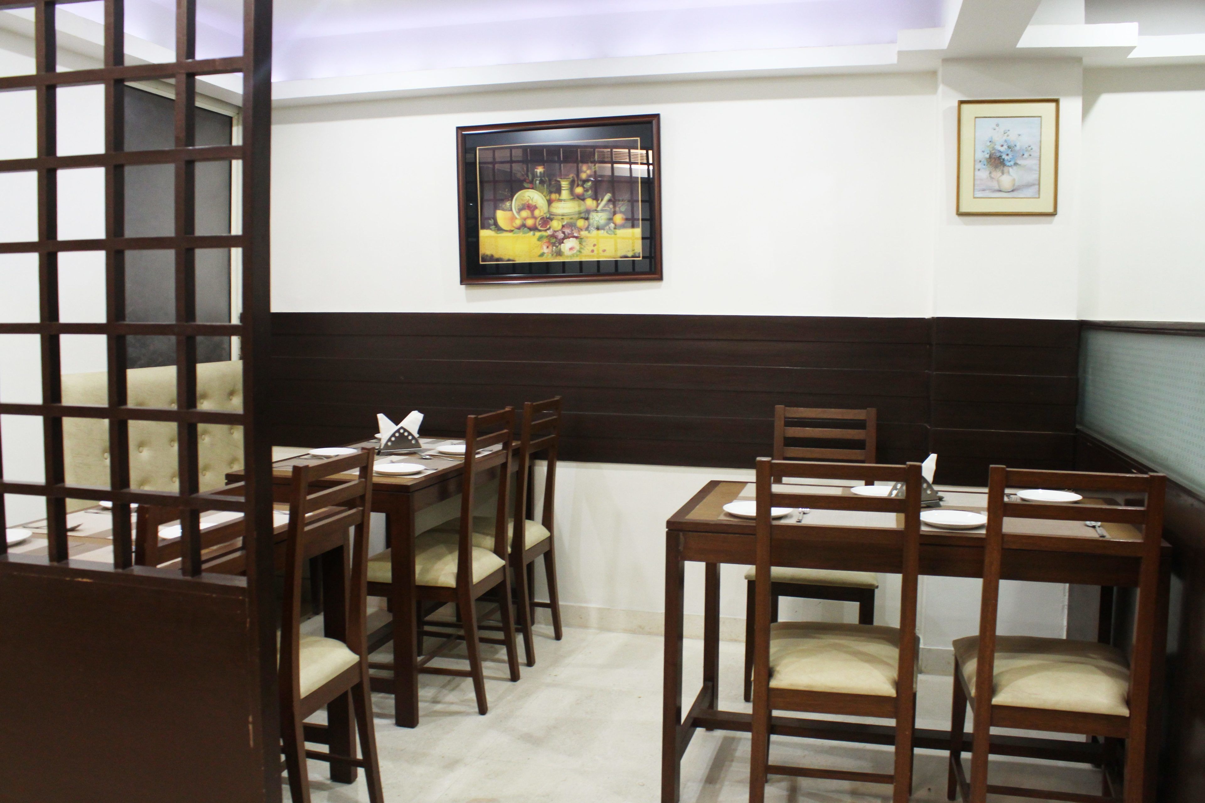 A dining area with wooden tables and chairs, a buffet setup, and a framed artwork on the wall.