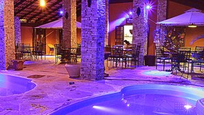 An outdoor pool area with stone pillars, tables, and chairs.