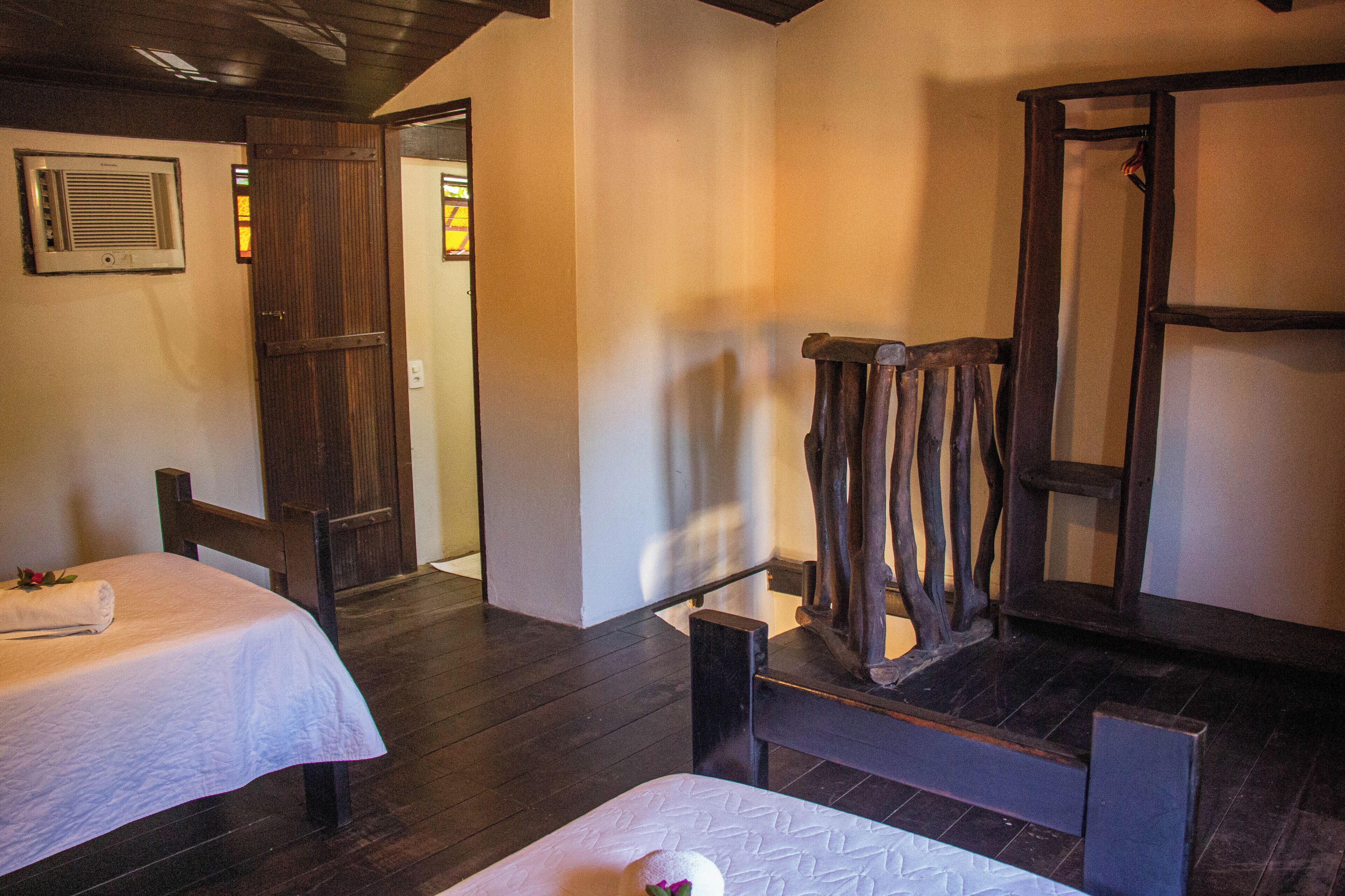 Une chambre d’hôtel avec deux lits, des meubles en bois et un grand miroir.