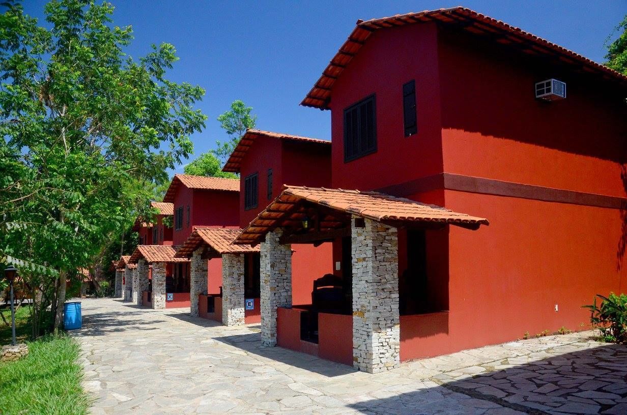 A row of red buildings with stone pillars and tiled roofs, arranged in a courtyard.