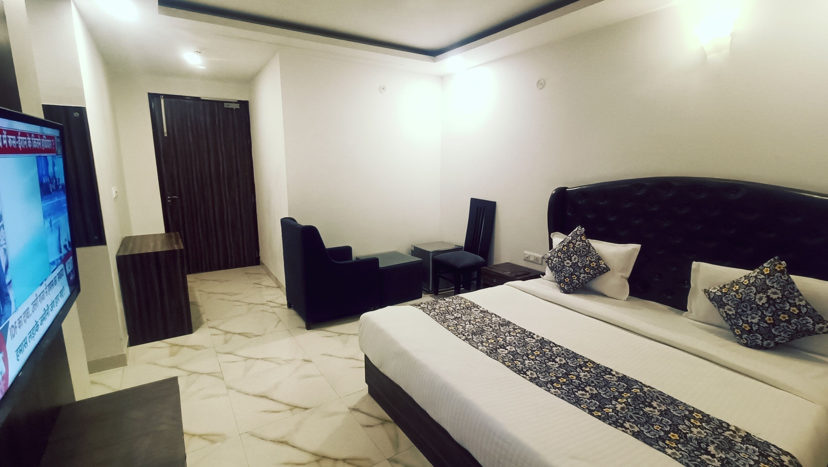 A hotel room with a bed, a desk, a chair, and a television.