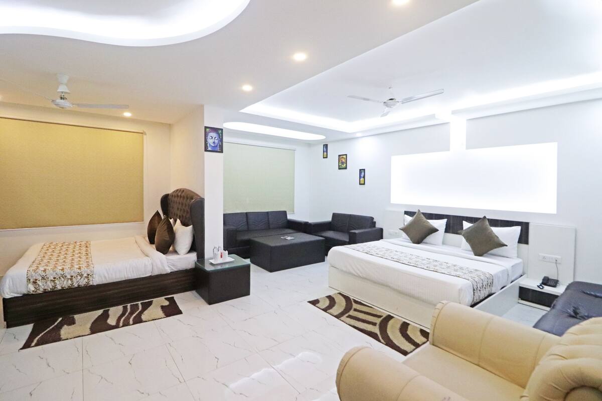 A modern hotel room with a large bed, a sofa, a desk, and a ceiling fan.
