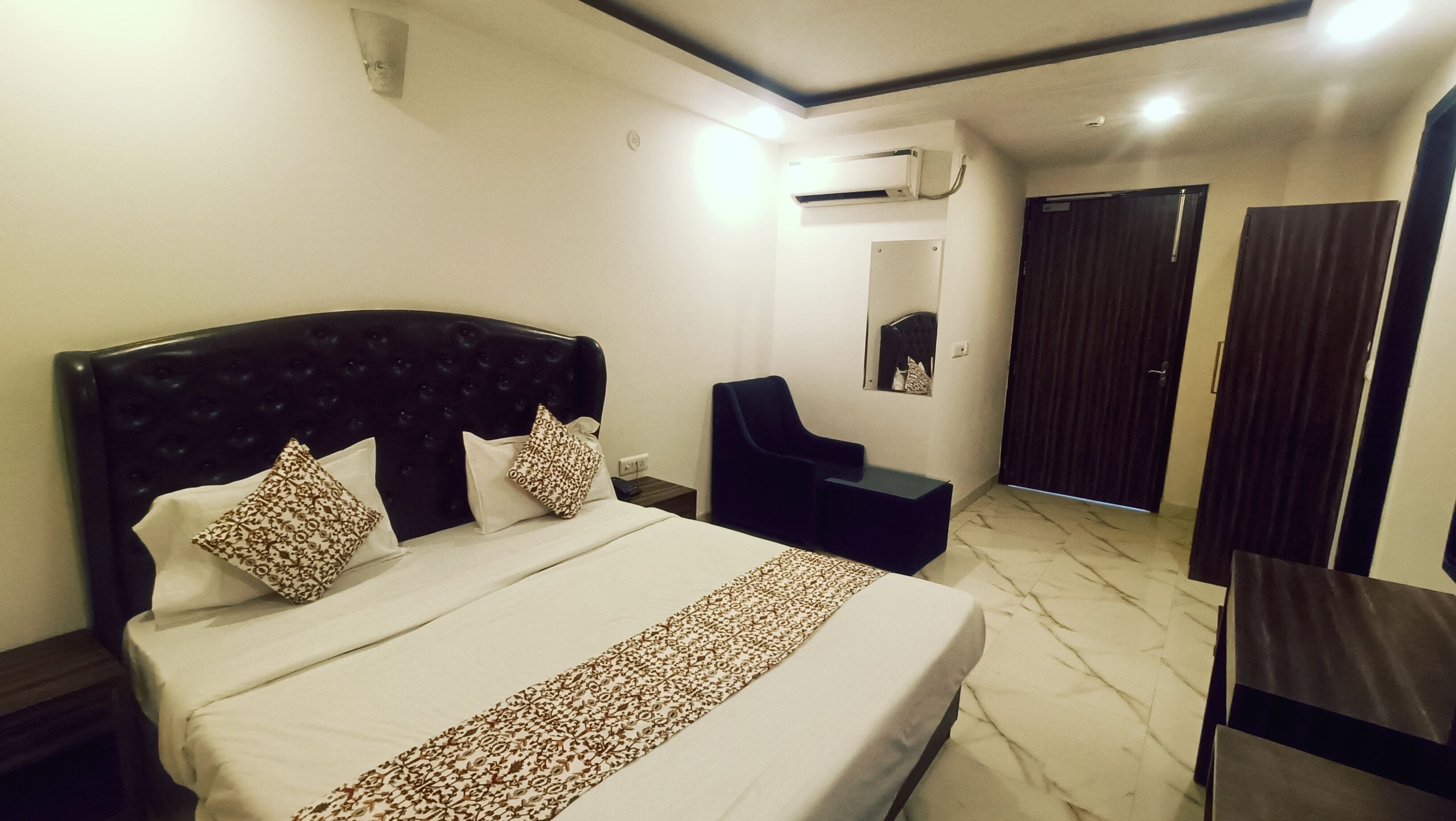 Una habitación de hotel con una cama grande, un escritorio pequeño, una silla, un armario y un equipo de aire acondicionado.
