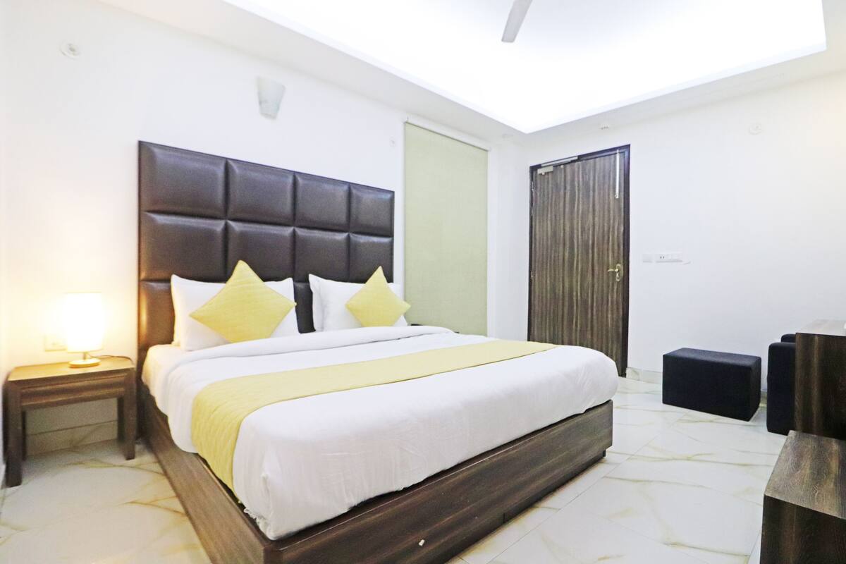 A modern hotel room with a large bed, a bedside lamp, a wardrobe, and a small table.