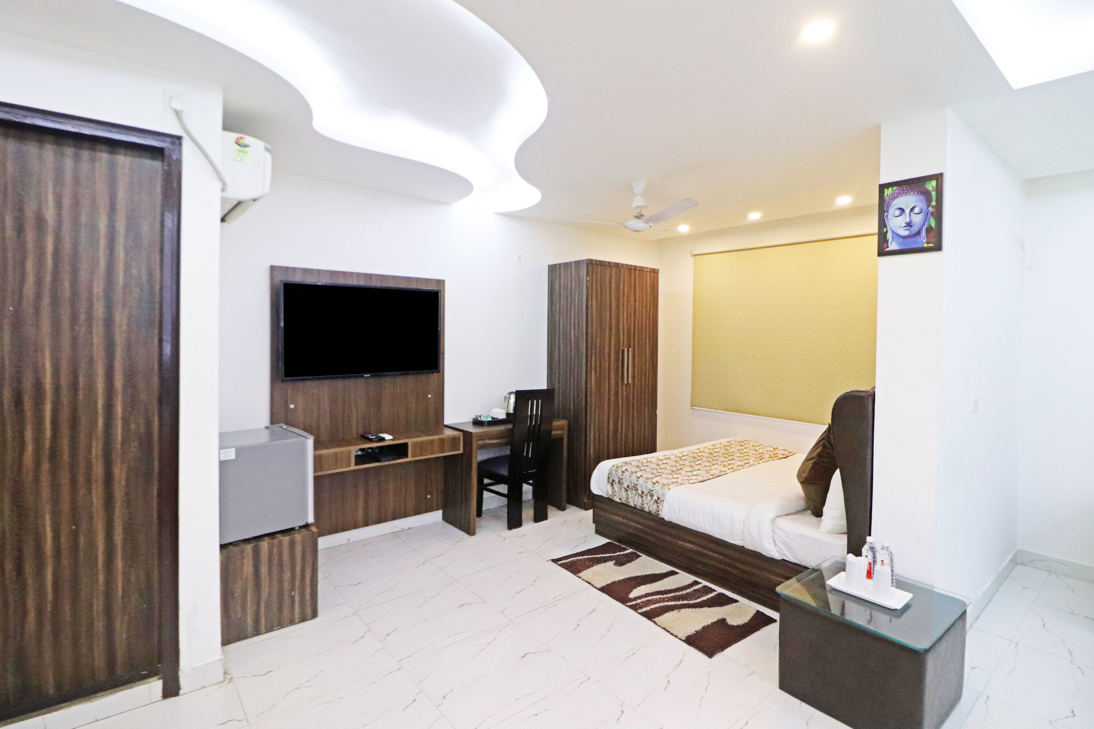 A modern hotel room with a bed, desk, chair, TV, and a ceiling fan.