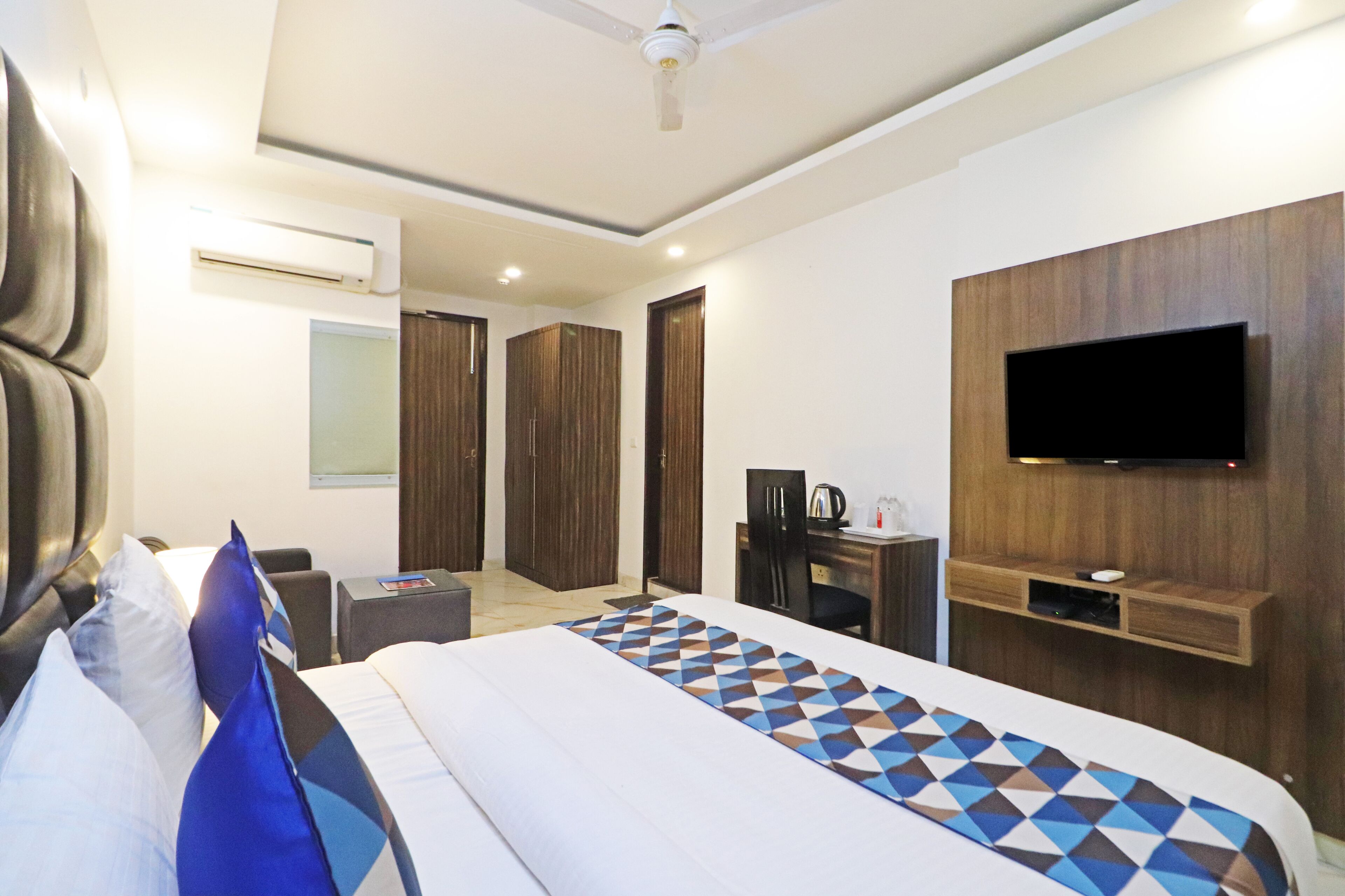 Camera d'albergo moderna con un letto grande, una TV a schermo piatto montata a parete, una scrivania con una sedia e un armadio.