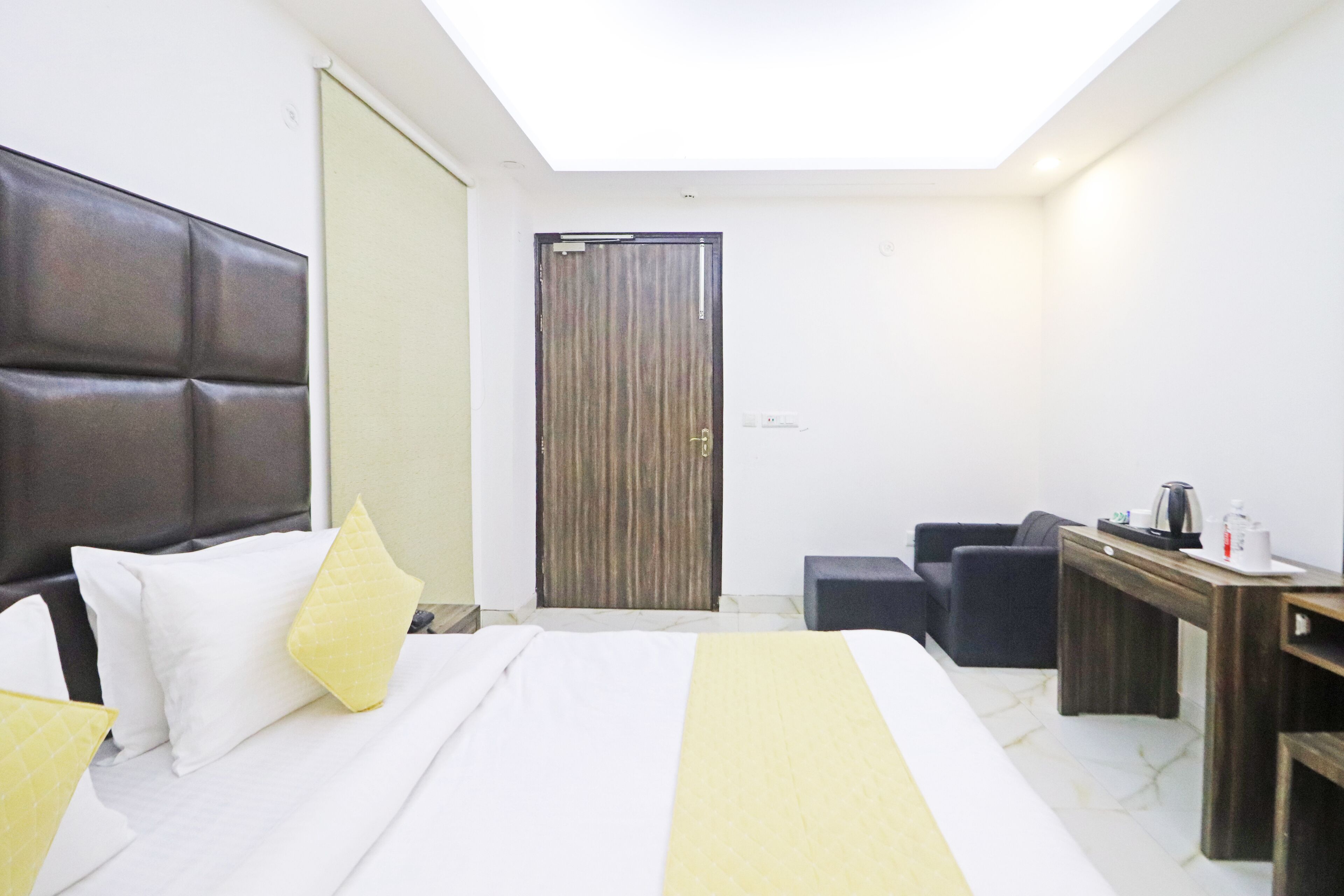 A hotel room with a bed, a desk, a chair, and a wardrobe.