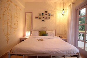 A neatly made bed with a book, a bedside lamp, and a wall decorated with framed pictures. - OYO 9788 Home 1 BHK Near LPK Waterfront (Candolim)