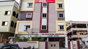 Ein mehrstöckiges Gebäude mit einem Schild für 'Prabhakar's' und 'OYO Hotel SSR Luxury'.