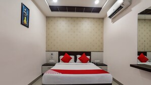 Ein Hotelzimmer mit Bett, Nachttischen, einem Spiegel und einer Klimaanlage.