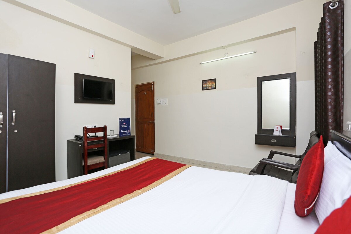 A hotel room with a bed, a desk, a chair, a TV, and a wardrobe.
