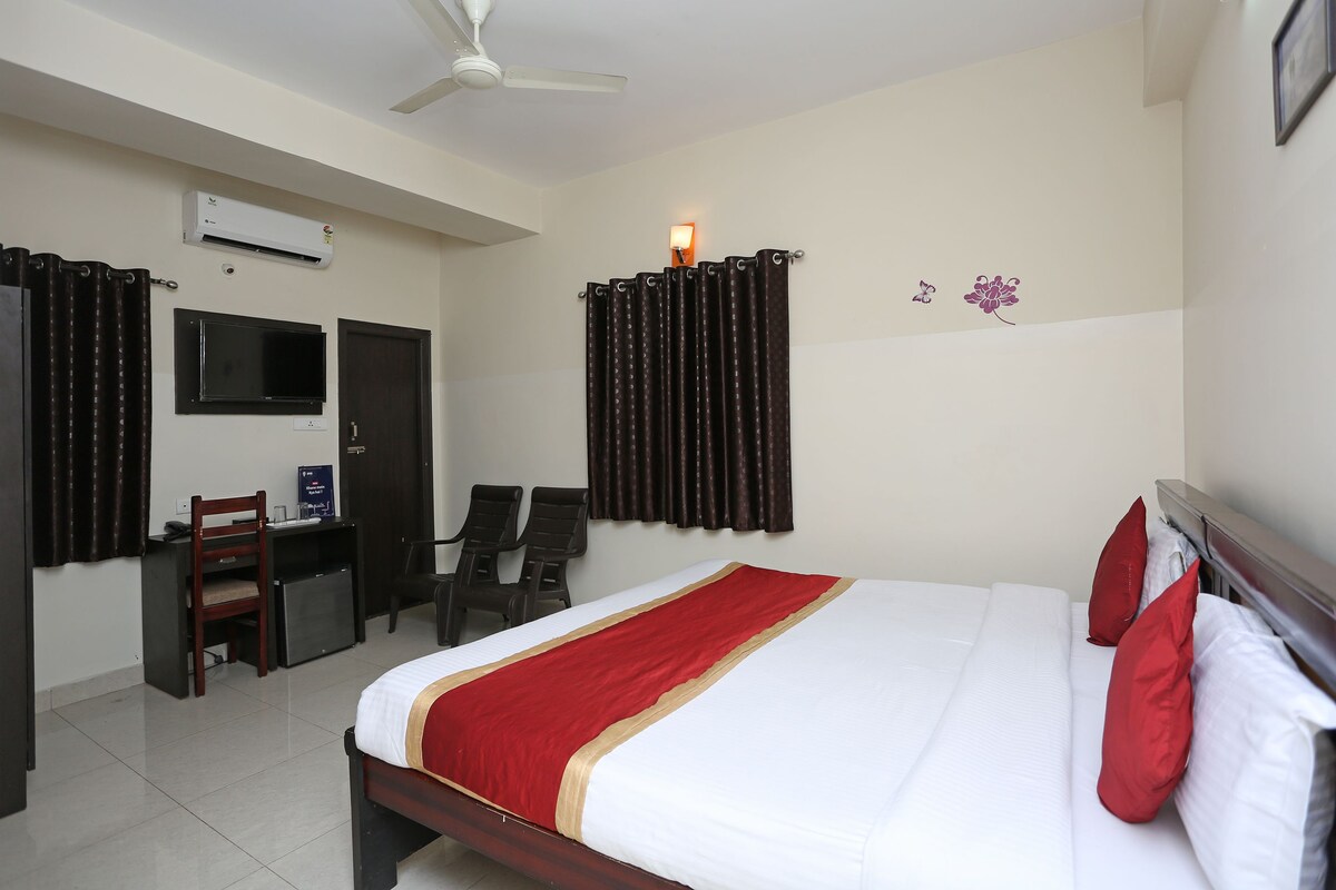 A hotel room with a bed, a desk, a chair, an air conditioner, and a ceiling fan.