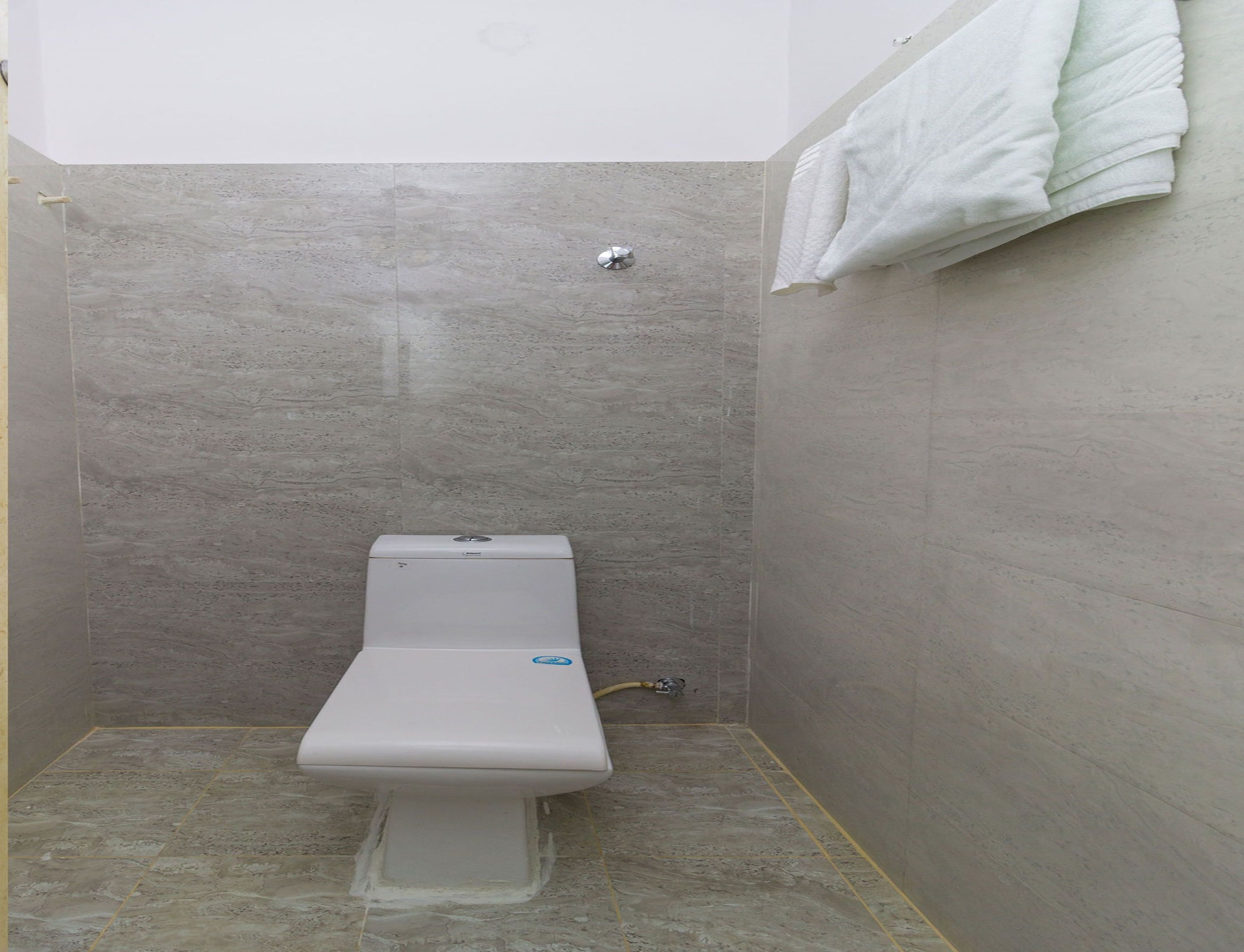 A small, enclosed shower area with a white toilet and a towel hanging on the wall.