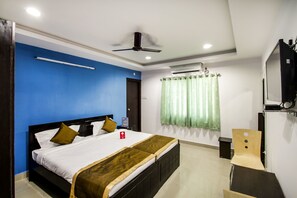 A bedroom with a bed, a ceiling fan, an air conditioning unit, a TV, and a window with curtains. - OYO Flagship 463 Banjara Hills (Hyderabad)