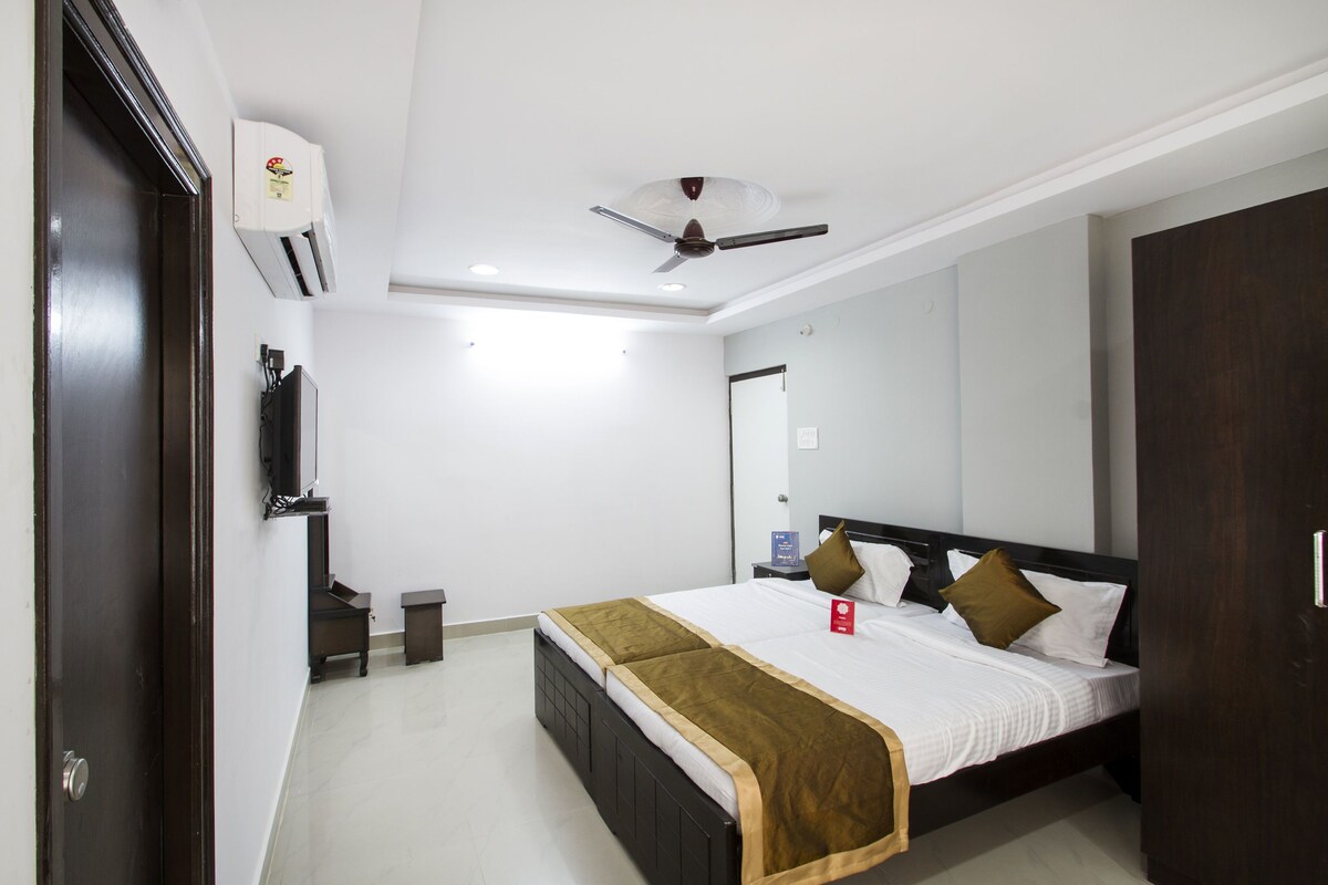 A hotel room with a bed, a ceiling fan, an air conditioning unit, a TV, and a wardrobe.